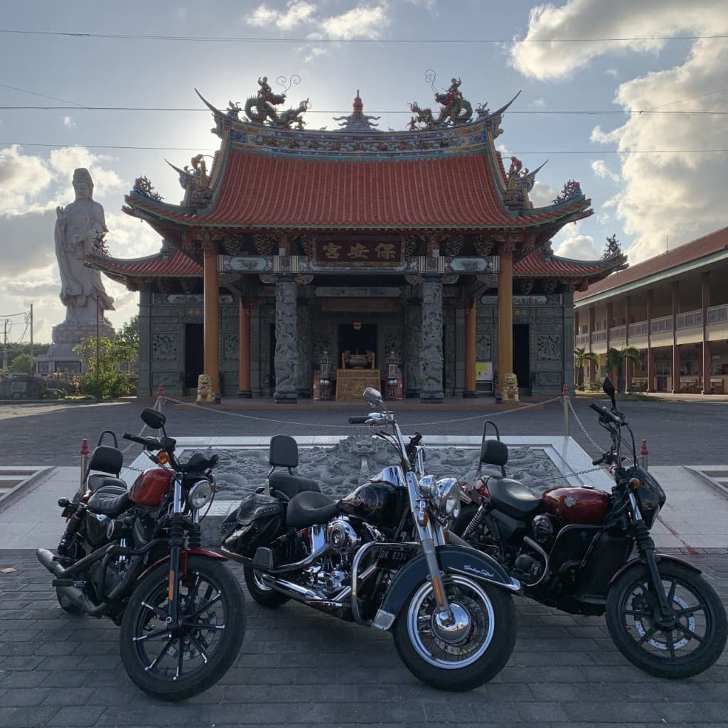 Three premium cruiser motorcycles at an ornate Balinese temple with deity statue — G-DRIVE Kintamani Highlands tour