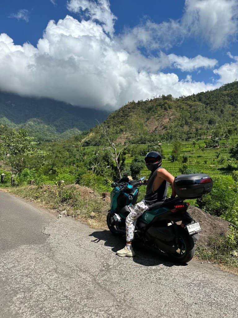 Rider on premium scooter overlooking lush green terraces on a Kintamani highland road